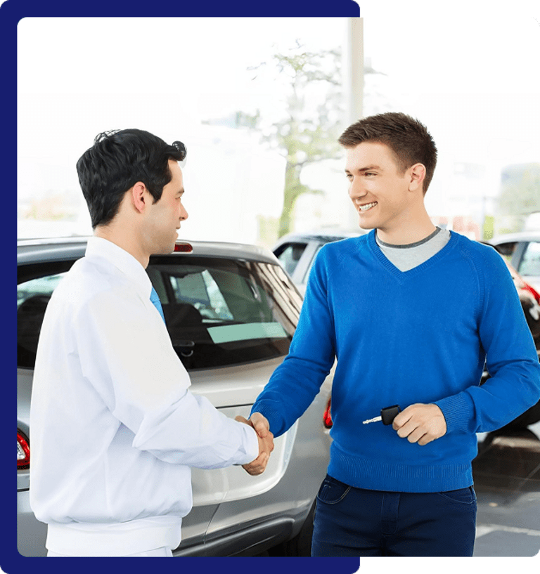 Two men shaking hands at car dealership.