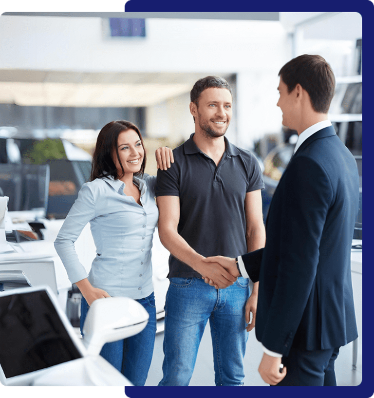 Car dealership handshake between three people.